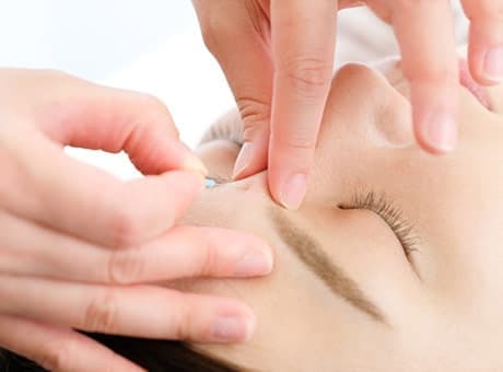 顔に鍼を打っている写真